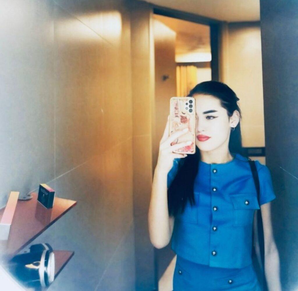 Woman with long hair taking mirror selfie in modern interior