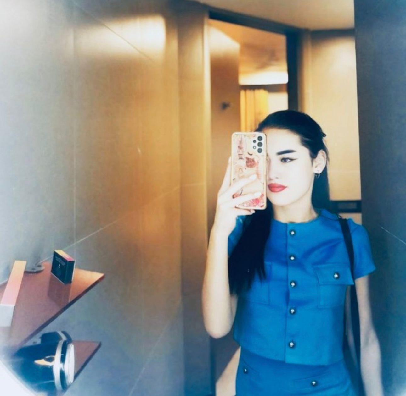 Woman with long hair taking mirror selfie in modern interior
