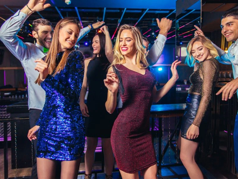 A group of boys and girls is celebrating and dancing in a modern nightclub